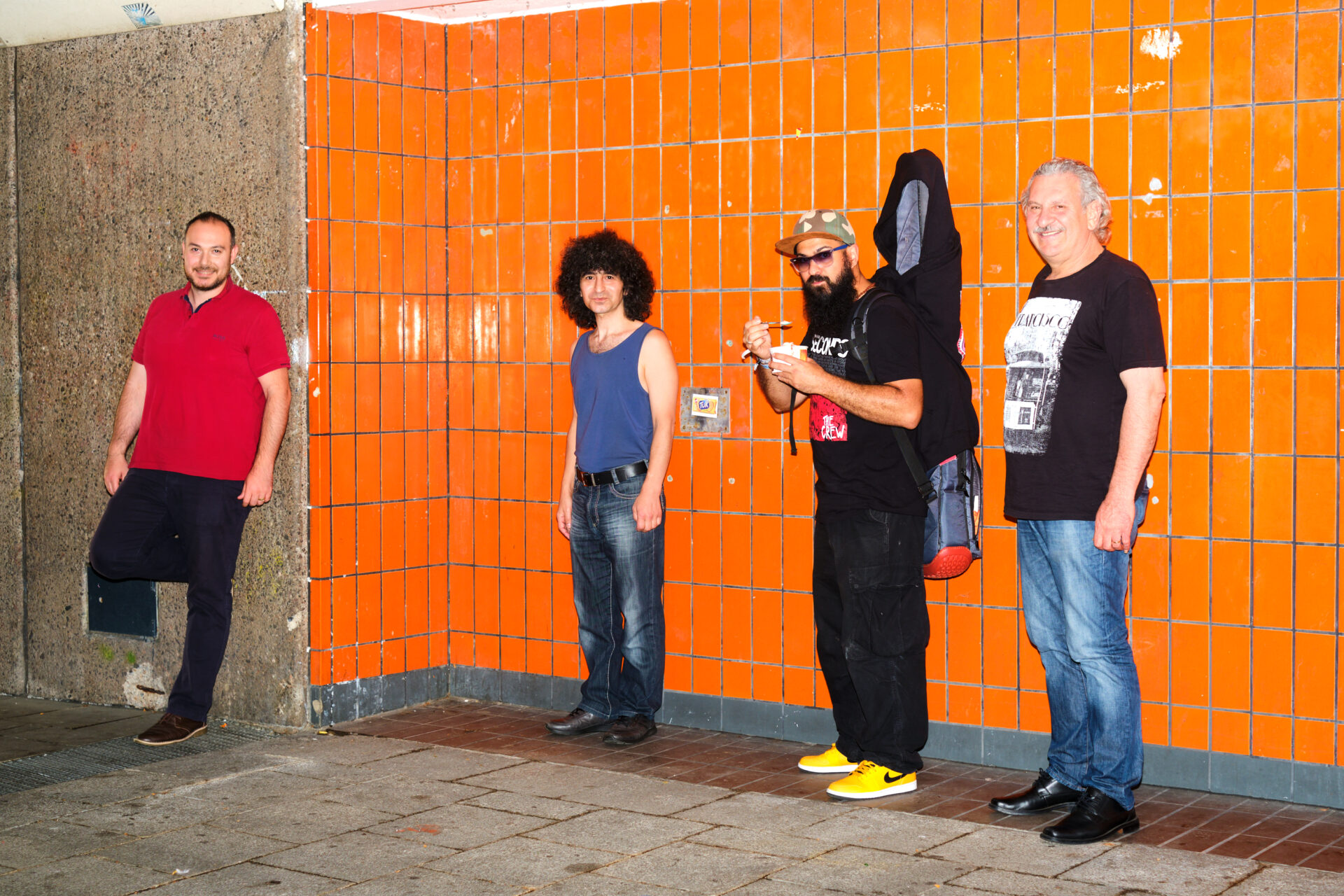 Vier Männer vor einer orange gefliesten Wand